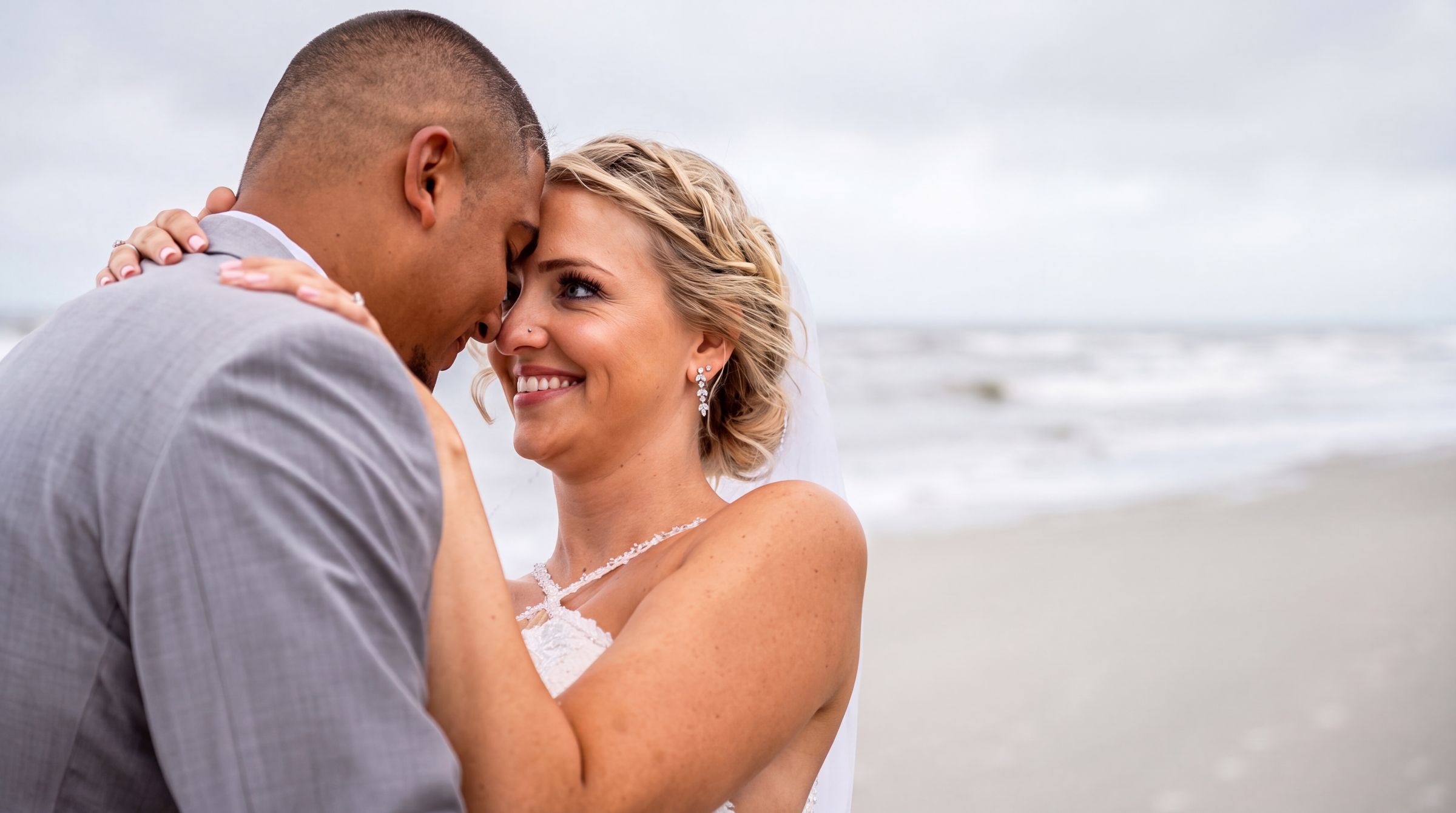 Bride and groom touching foreheads on the beach