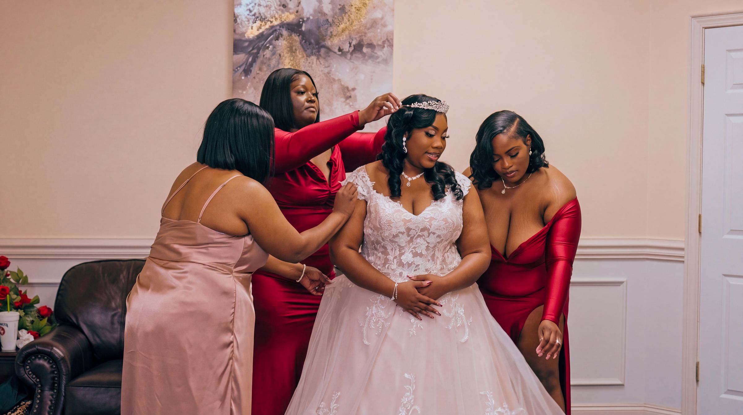 Bride surrounded by bridesmaids as they help her into her wedding dress