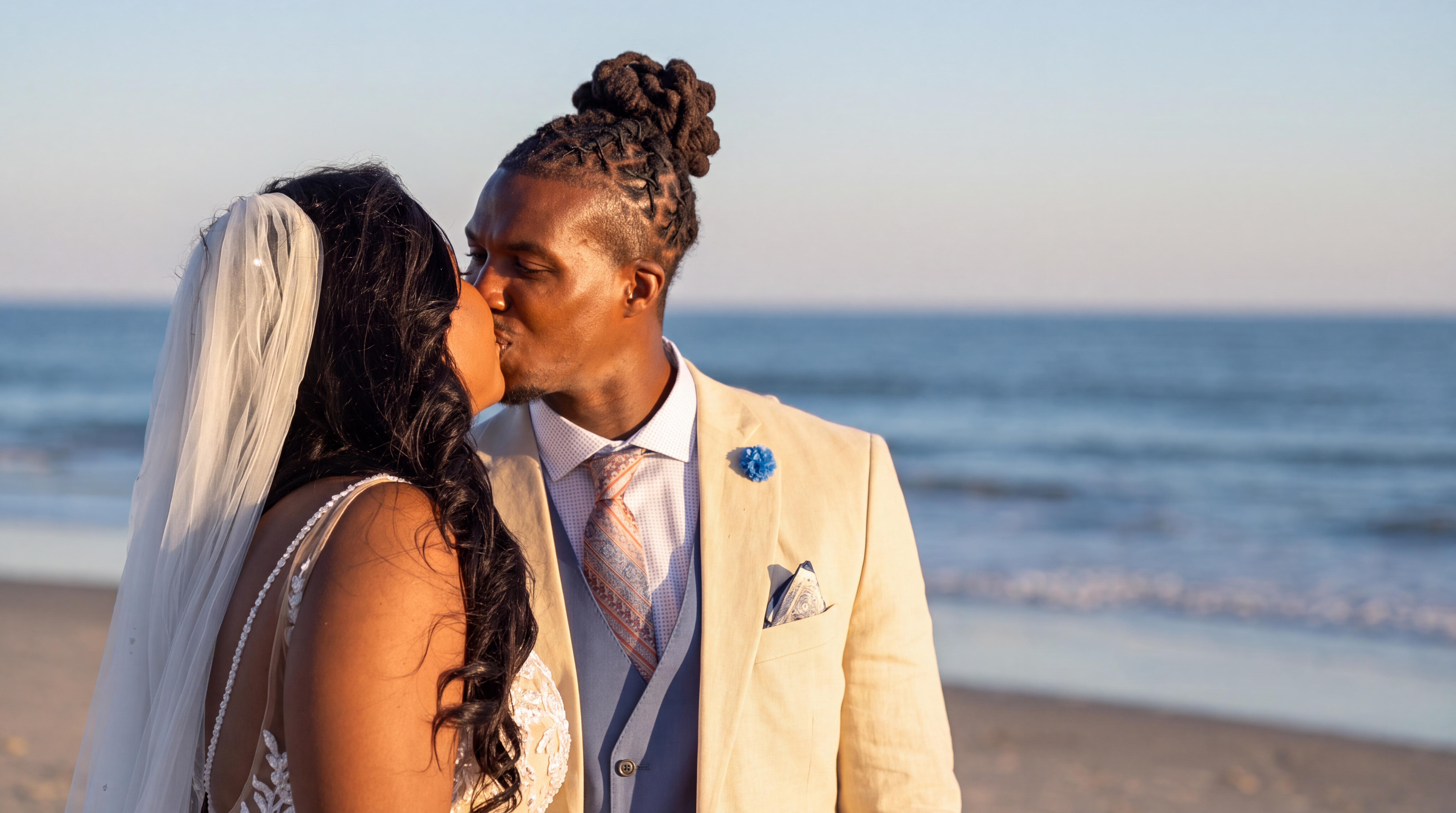 Bride and groom kissing on the beach during their wedding portrait session