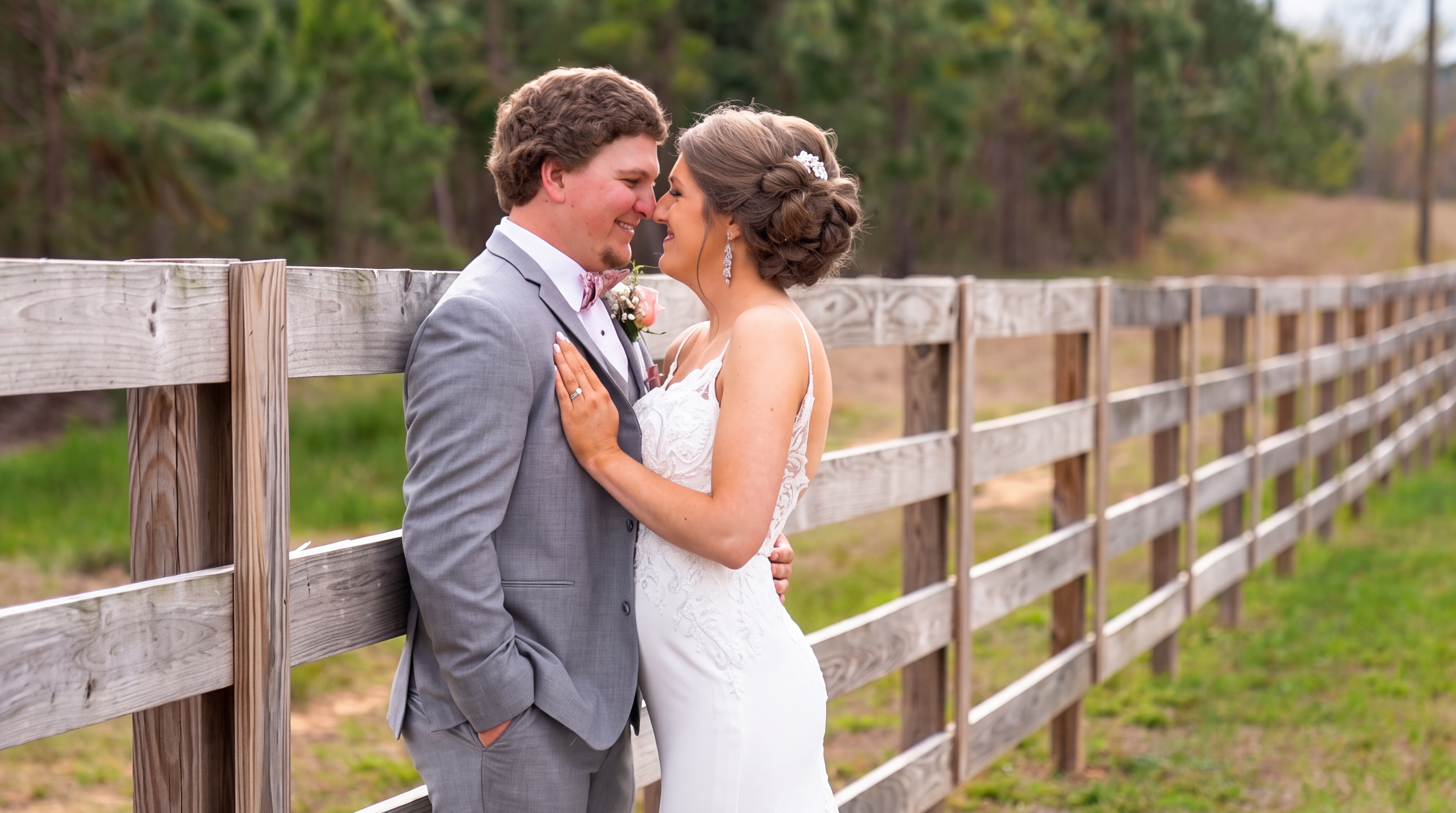 Bride and groom embracing beside a wooden fence during their wedding portrait session